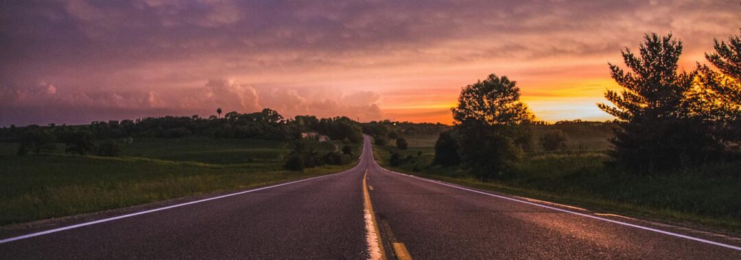 photo of empty road in between grass field during golden hour