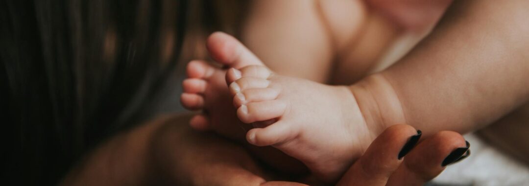 person holding baby s feet in selective focus photography